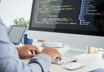 Profissional de TI PJ organizando contrato e emissão de NFS-e em notebook.